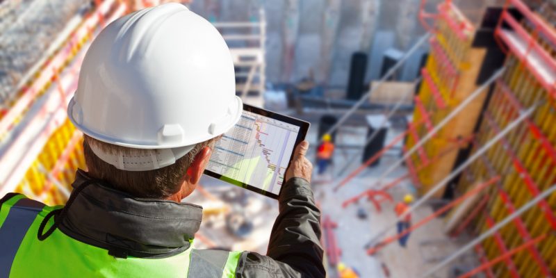civil engineer or architect on construction site checking schedule with tablet computer